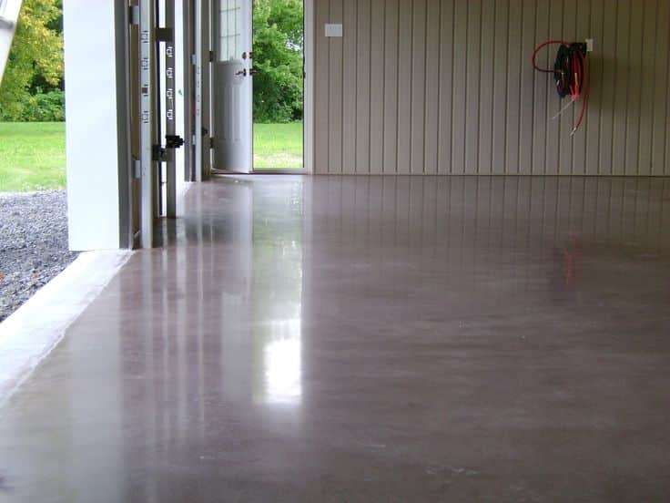 Polished concrete floor in an open garage with a view of greenery outside through the door.