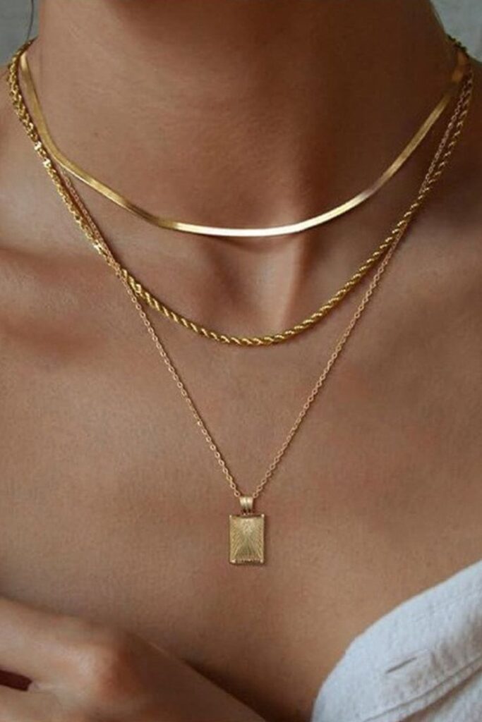 Geometric Square Pendant Layered Necklace Elegant layered gold necklaces on a model's neck, showcasing a trendy rectangle pendant and smooth chains. | Sky Rye Design Elegant layered gold necklaces on a model's neck, showcasing a trendy rectangle pendant and smooth chains.