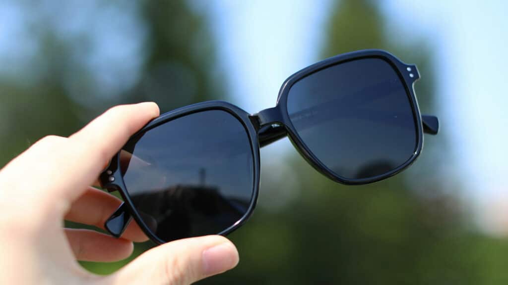 Getting the Width Right Hand holding stylish black sunglasses against a blurred natural background. | Sky Rye Design Hand holding stylish black sunglasses against a blurred natural background.