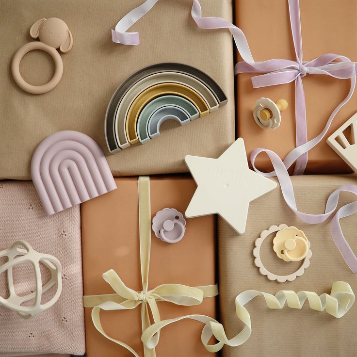 Gift Card - _00 USD Gift-wrapped baby toys with pastel ribbons, featuring rainbows, stars, and teethers on a beige background. | Sky Rye Design Gift-wrapped baby toys with pastel ribbons, featuring rainbows, stars, and teethers on a beige background.