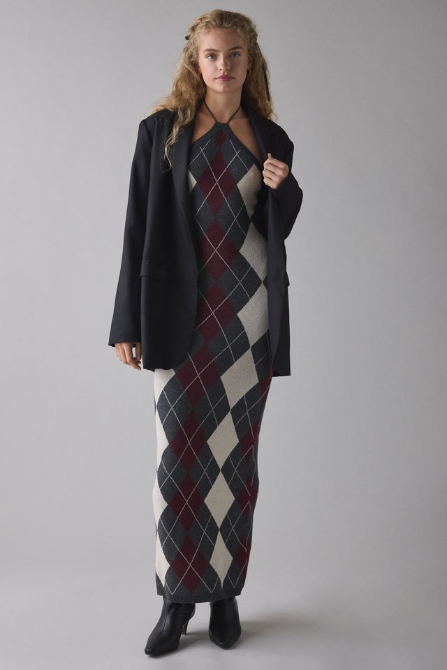 Glamorous Charcoal Argyle Knit High Neck Halter Maxi Dress Woman in argyle dress and black blazer poses confidently against a plain background. | Sky Rye Design Woman in argyle dress and black blazer poses confidently against a plain background.