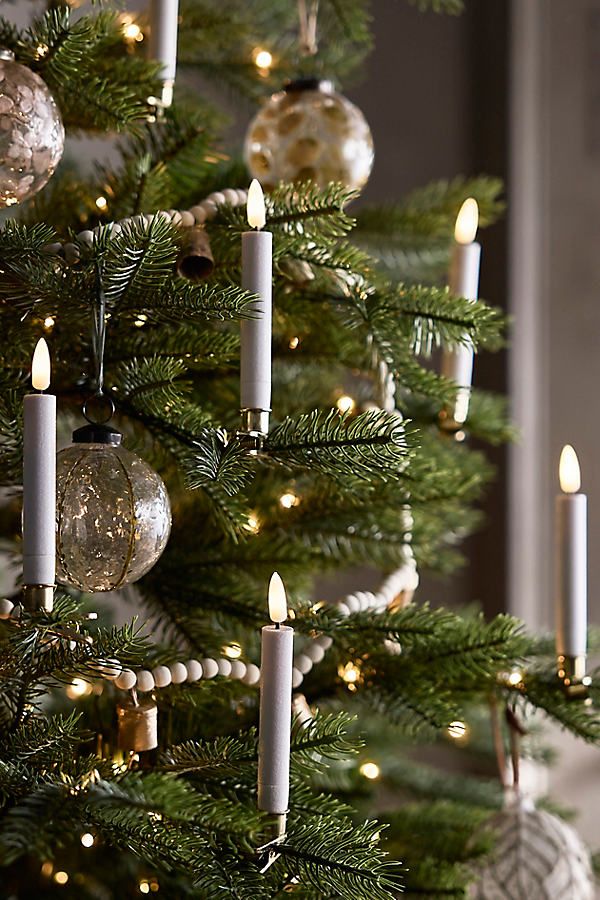 Elegant Christmas tree with lit candles, ornaments, and bead garland for festive holiday decor.