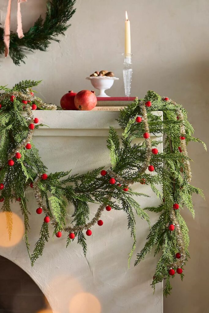 Good Cheer Bauble Ornament Tinsel Garland Festive mantel with greenery, red berries, pomegranates, candle, and nuts creates cozy holiday decor atmosphere. | Sky Rye Design Festive mantel with greenery, red berries, pomegranates, candle, and nuts creates cozy holiday decor atmosphere.