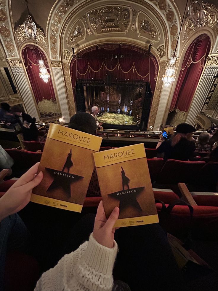 Hamilton ⭐️🎶 Audience at a theater holding Hamilton playbills, viewing the stage from mezzanine seats. | Sky Rye Design Audience at a theater holding Hamilton playbills, viewing the stage from mezzanine seats.