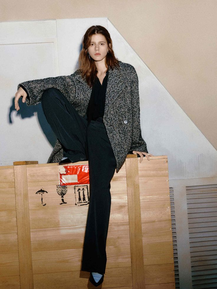 Herringbone Tweed Jacket - Grey _ S Fashionable person in a herringbone coat sitting on a wooden crate, exuding modern elegance and sophistication. | Sky Rye Design Fashionable person in a herringbone coat sitting on a wooden crate, exuding modern elegance and sophistication.