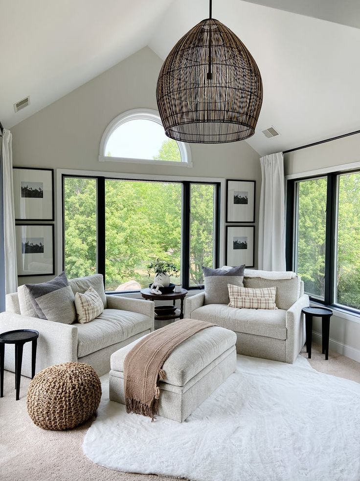 Modern living room with large windows, cozy sofas, and a woven pendant light. Neutral tones create a relaxing atmosphere.