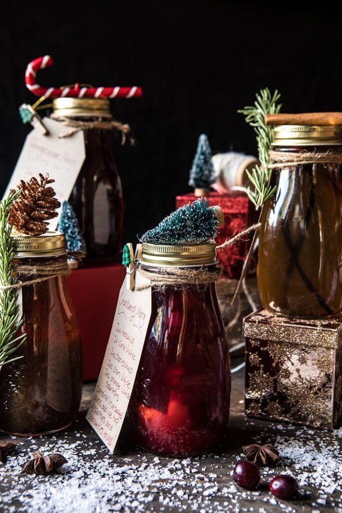 Holiday Gifting_ Homemade Simple Syrups_ Festive holiday jars with homemade drinks, garnished with decorations and tags, surrounded by snow and cranberries. | Sky Rye Design Festive holiday jars with homemade drinks, garnished with decorations and tags, surrounded by snow and cranberries.