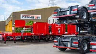 Red trailers at Dennison facility, showcasing advanced logistics equipment against a clear sky.