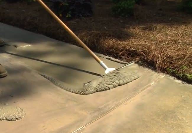 Smoothing concrete with a rake on a sidewalk for even texture and finish.