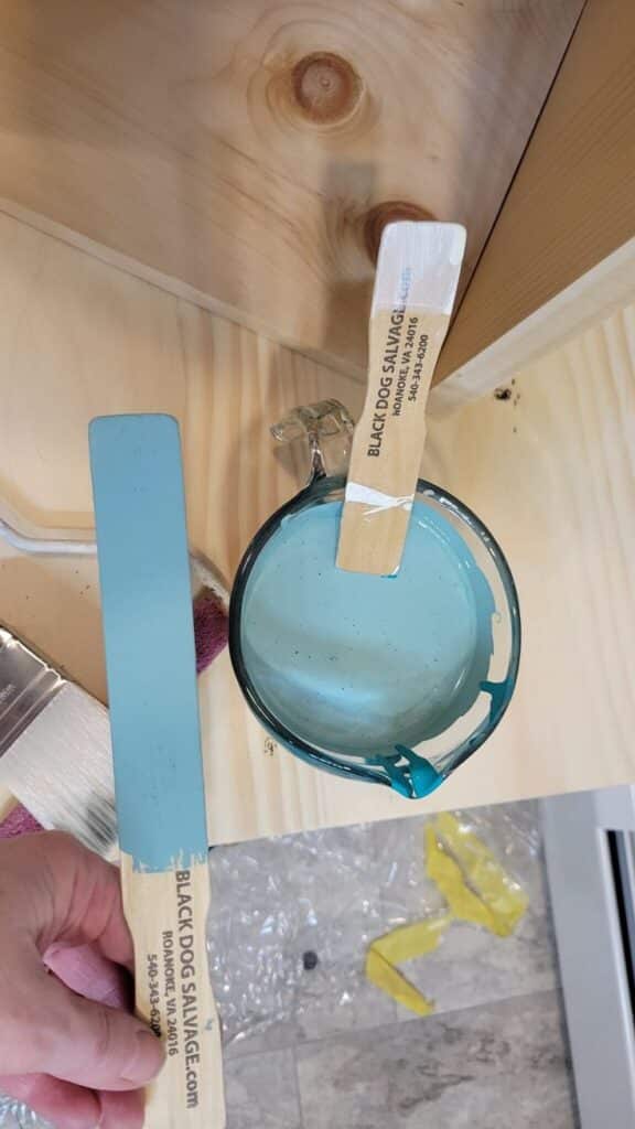 How to Get a Professional Smooth Paint Finish Blue paint in a cup with wooden stirrers on a wooden surface, ready for painting project. | Sky Rye Design Blue paint in a cup with wooden stirrers on a wooden surface, ready for painting project.