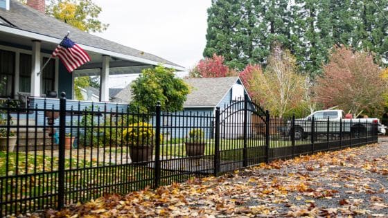 How to Guarantee Comfort Value and Curb Appeal of Home Improvements Suburban house with black metal fence, American flag, and colorful autumn leaves on the ground. | Sky Rye Design Suburban house with black metal fence, American flag, and colorful autumn leaves on the ground.