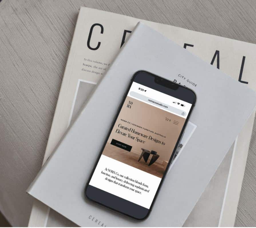 Smartphone displaying NOMA Co. homeware site on a table with a Cereal magazine underneath.