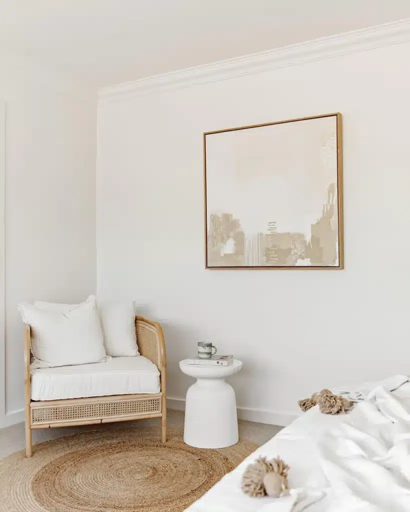 IMG_4875BB614C73-1_1_jpg_1024x Minimalist bedroom with rattan chair, abstract art, white side table, and round jute rug. | Sky Rye Design Minimalist bedroom with rattan chair, abstract art, white side table, and round jute rug.