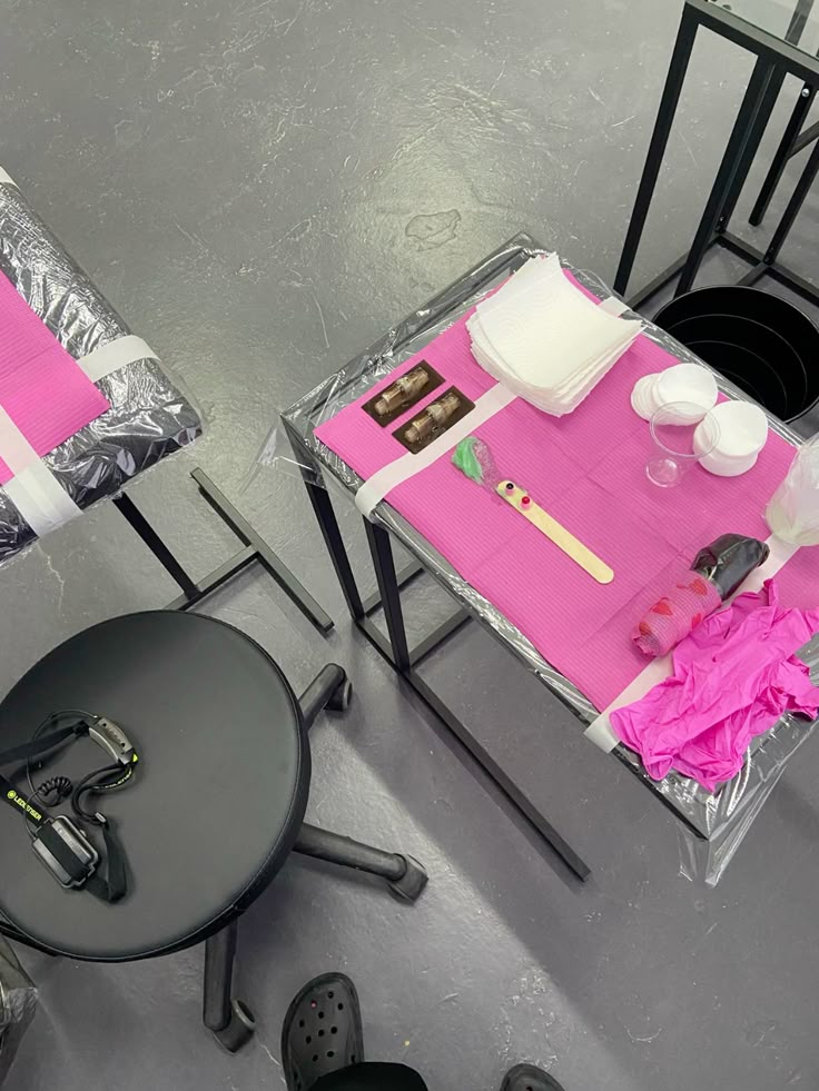 Instagram yanimakestattoo Tattoo station with pink covers, gloves, ink cups, and tools on gray floor background. | Sky Rye Design Tattoo station with pink covers, gloves, ink cups, and tools on gray floor background.
