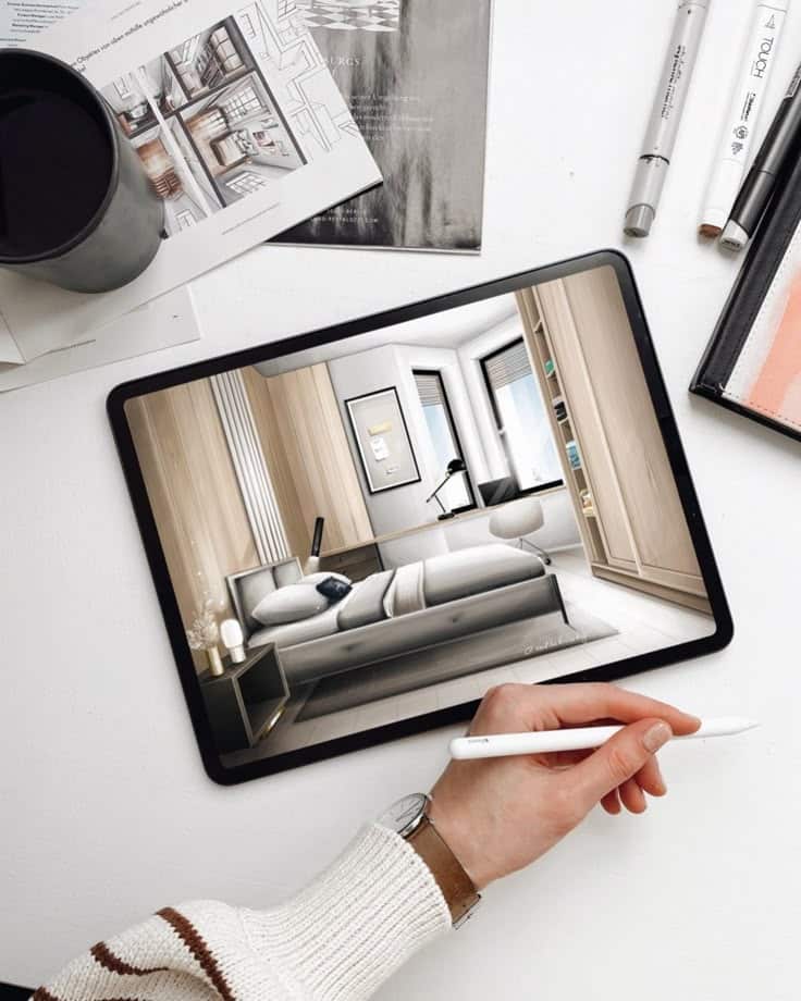 Interior Design on iPad Tablet displaying a modern bedroom design, surrounded by markers, a cup, and architectural papers on a white table. | Sky Rye Design Tablet displaying a modern bedroom design, surrounded by markers, a cup, and architectural papers on a white table.
