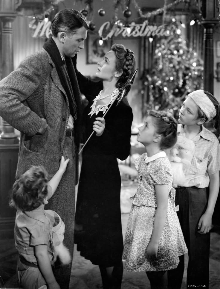 Vintage Christmas scene with a family gathered around a tree, exchanging joyful holiday wishes.