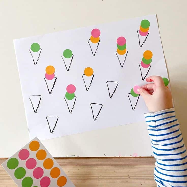 Jennifer little_play_ideas on Instagram_ Stickers are one of my favourite fine motor resources because they make for some really easy activities and children love them_ Peeling the Child sticking colorful dot stickers on paper ice cream cones craft. | Sky Rye Design Child sticking colorful dot stickers on paper ice cream cones craft.