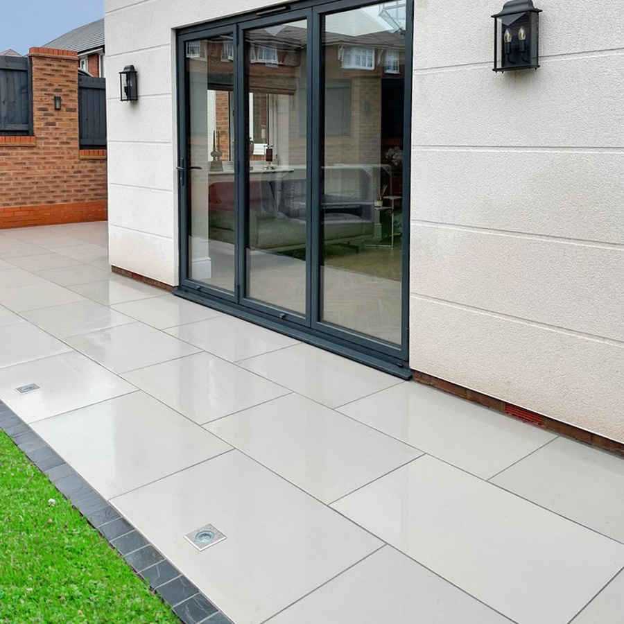 Modern backyard patio with sleek tiles and glass doors for a stylish outdoor living area.
