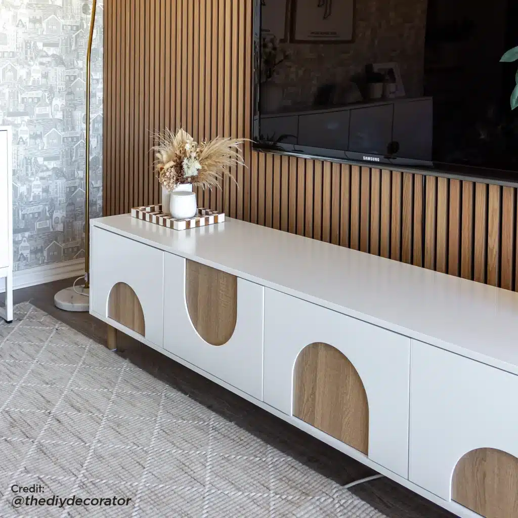 LCESPUR-ENT-WHT_2a1 Modern living room with a sleek, white TV stand, wooden accents, and a stylish vase on top. Elegant interior design. | Sky Rye Design Modern living room with a sleek, white TV stand, wooden accents, and a stylish vase on top. Elegant interior design.