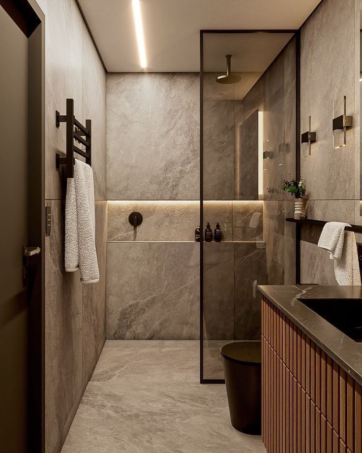 Modern bathroom with stone walls, glass shower, sleek vanity, and warm lighting enhancing elegant interior design.