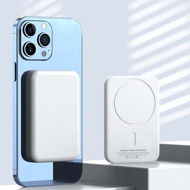 Blue smartphone with attached magnetic wireless power bank and separate charging pad on a white surface.