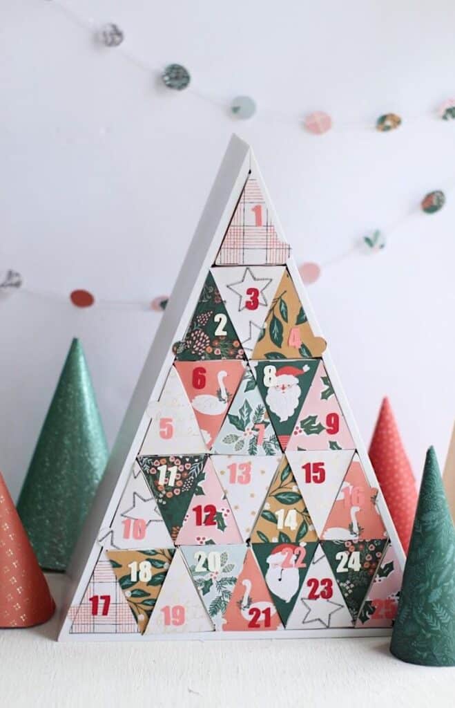 Make a Silhouette Advent Calendar Triangular advent calendar with colorful numbered sections and festive designs, surrounded by decorative trees. | Sky Rye Design Triangular advent calendar with colorful numbered sections and festive designs, surrounded by decorative trees.