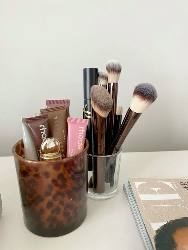 Makeup Makeup brushes and tubes in holders on a desk, styled with a fashion magazine nearby. | Sky Rye Design Makeup brushes and tubes in holders on a desk, styled with a fashion magazine nearby.