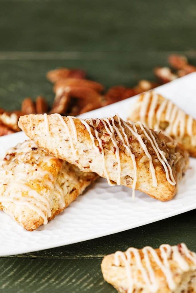 Maple Bourbon Pecan Scones Delicious pecan scones with icing drizzle on a white plate, perfect for a sweet breakfast treat. | Sky Rye Design Delicious pecan scones with icing drizzle on a white plate, perfect for a sweet breakfast treat.