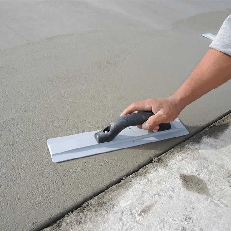 Hand smoothing wet concrete with a trowel for a clean finish.