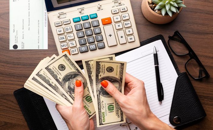 Maximizing Efficiency in Cash Flow Management Person counting cash at a desk with calculator, notebook, glasses, a succulent plant, and a check in the background. | Sky Rye Design Person counting cash at a desk with calculator, notebook, glasses, a succulent plant, and a check in the background.