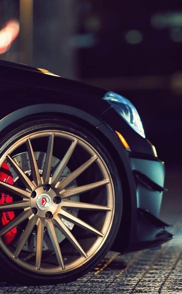 Close-up of a luxury car's bronze alloy wheel and headlight, showcasing sleek design and performance brakes.