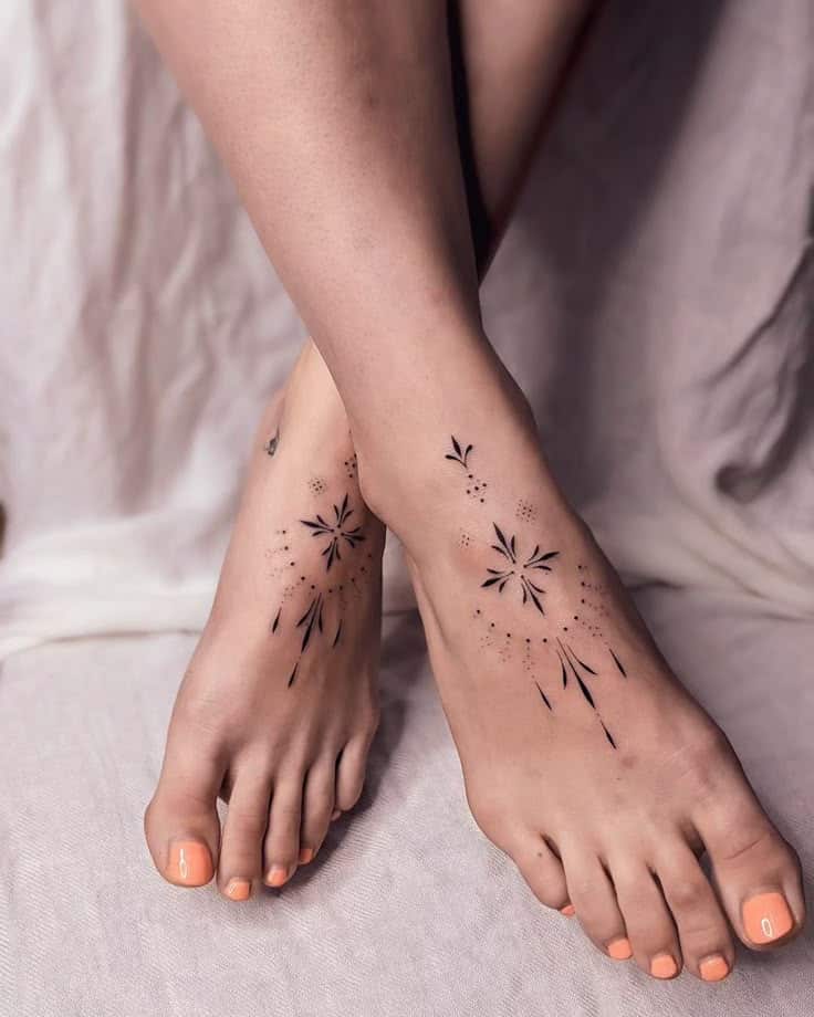 Minimalist Feet Tattoo Designs for Women Feet with geometric flower tattoos and peach nails on a soft fabric background. | Sky Rye Design Feet with geometric flower tattoos and peach nails on a soft fabric background.