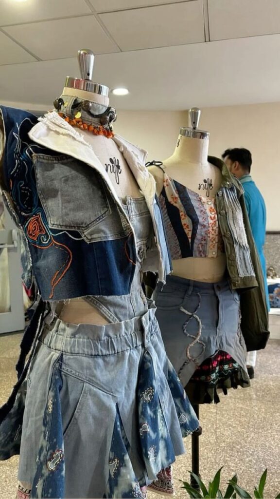 Mannequins wearing creative denim outfits, showcasing unique patchwork designs in a fashion studio setting.