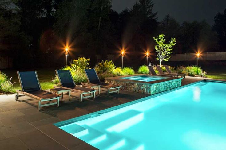 Natural Swimming Pools - Derby City Pools Louisville KY Illuminated backyard pool with deck chairs and ambient lighting at night, surrounded by lush greenery. | Sky Rye Design Illuminated backyard pool with deck chairs and ambient lighting at night, surrounded by lush greenery.