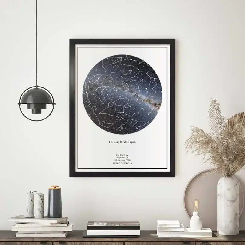Framed star map art on a minimalist shelf, featuring constellations and personalized location details.