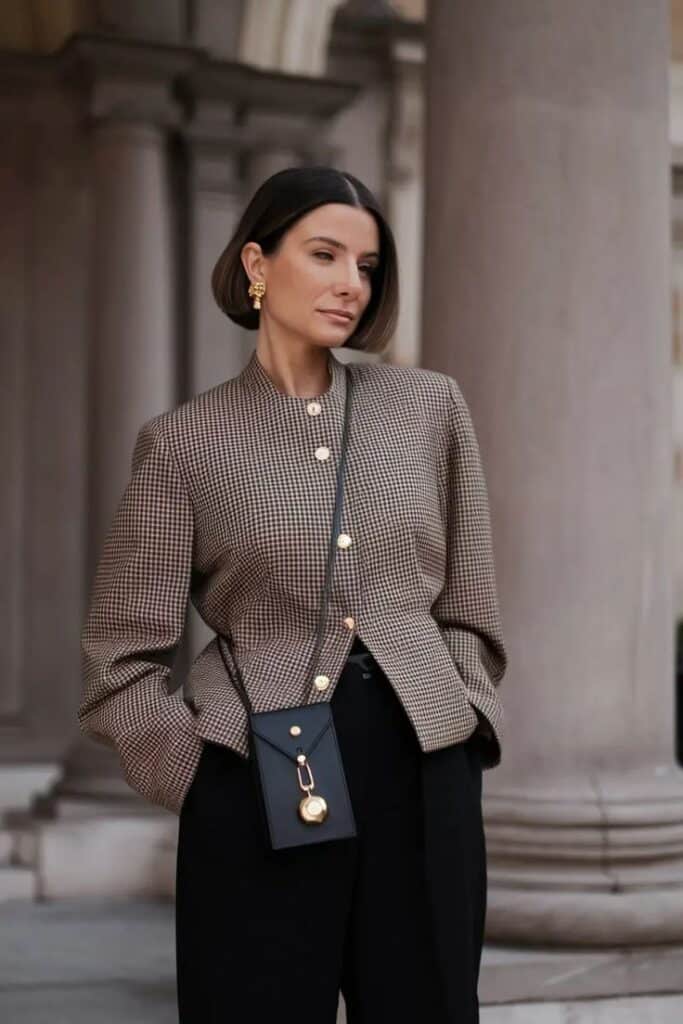 New Ideas 2025 Fall Style for Women_ Fresh Outfits to Inspire Your Autumn Wardrobe Fashionable woman in checked blazer, bold earrings, and crossbody bag, standing by columns. Sophisticated urban style. | Sky Rye Design Fashionable woman in checked blazer, bold earrings, and crossbody bag, standing by columns. Sophisticated urban style.