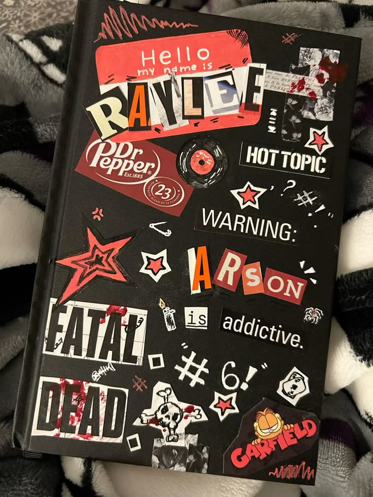 Decorated notebook cover with collage of various stickers and text including Dr. Pepper and Garfield graphics.