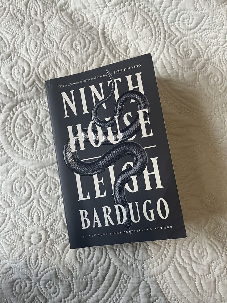Ninth House by Leigh Bardugo Ninth House book by Leigh Bardugo with snake design on a quilted white bedspread. | Sky Rye Design Ninth House book by Leigh Bardugo with snake design on a quilted white bedspread.