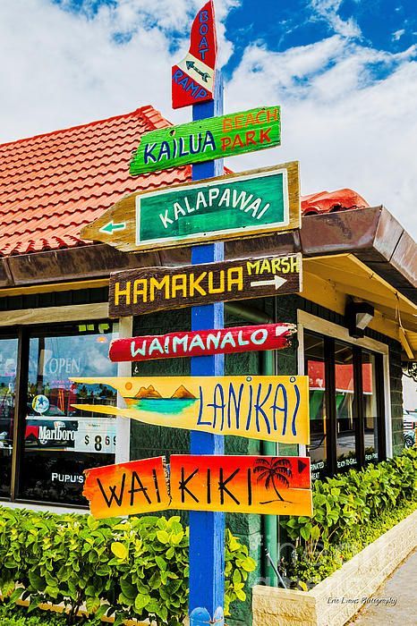 Colorful direction signs to Hawaiian beaches and landmarks, including Kailua, Lanikai, and Waikiki, outside a shop.
