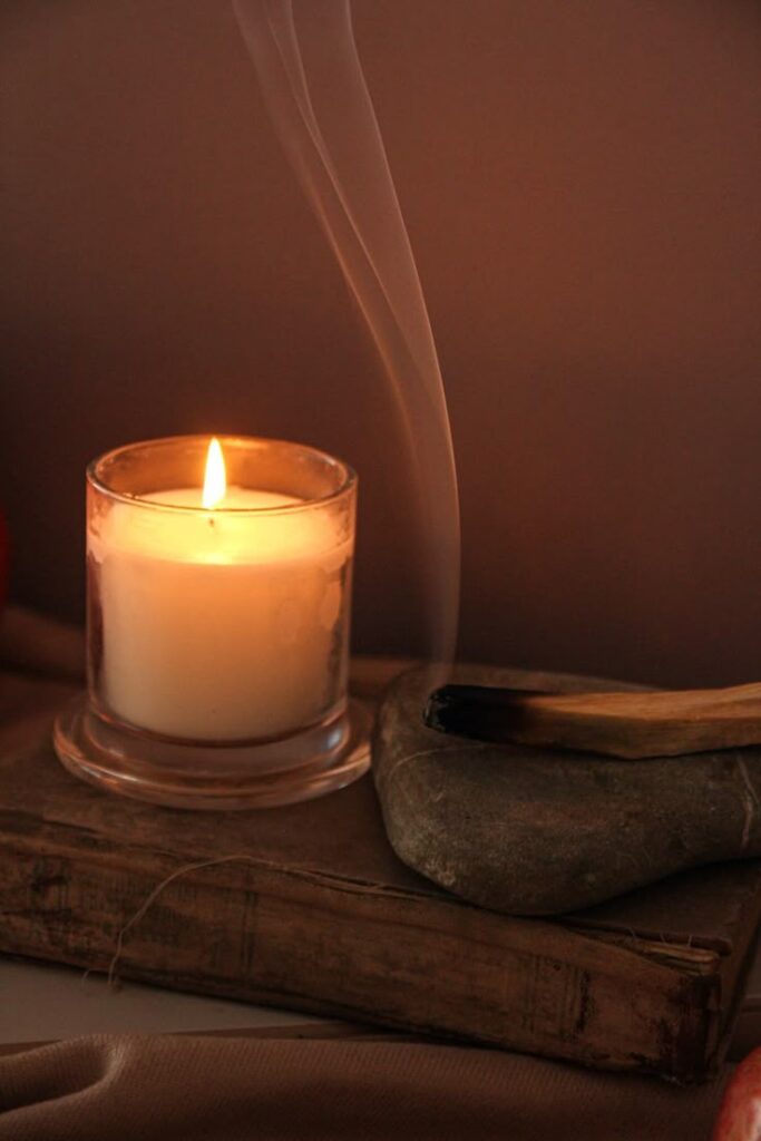 Palo santo Lit candle on a book with extinguished incense, creating a calming and soothing atmosphere. | Sky Rye Design Lit candle on a book with extinguished incense, creating a calming and soothing atmosphere.