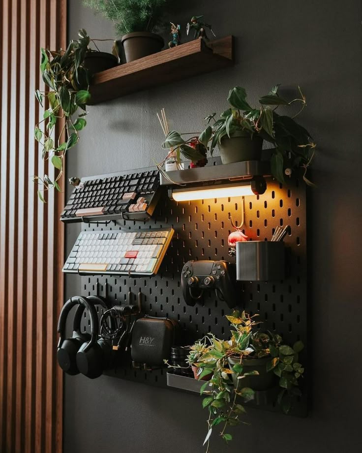 Wall-mounted organizer with plants, keyboard, headphones, controller, and lighting on a dark background.