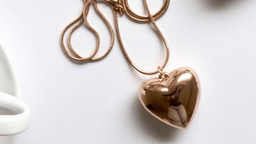 Gold heart-shaped pendant necklace on a white background, showcasing elegant jewelry design.
