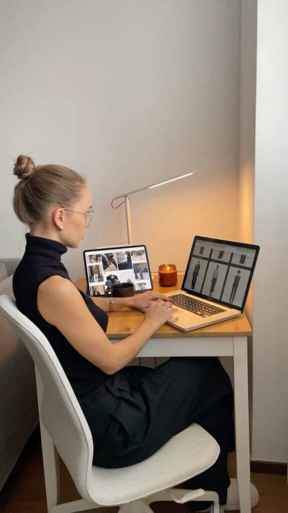 Personal stylist Spain aesthetic home office_ My instagram_ natalimarre Woman working on laptop at home office desk, surrounded by candles and a tablet displaying fashion images. | Sky Rye Design Woman working on laptop at home office desk, surrounded by candles and a tablet displaying fashion images.