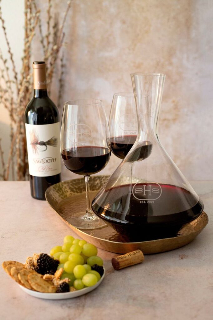 Personalized Wine Decanter Angled Wine Decanter Crystal Wine Decanter Deep Etched Personalized Couples Wedding Gift Decanter and wine glasses with red wine, grapes, and snacks on a table for an elegant tasting experience. | Sky Rye Design Decanter and wine glasses with red wine, grapes, and snacks on a table for an elegant tasting experience.
