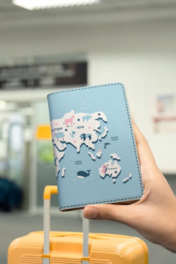 Person holding world map passport cover at airport with luggage.