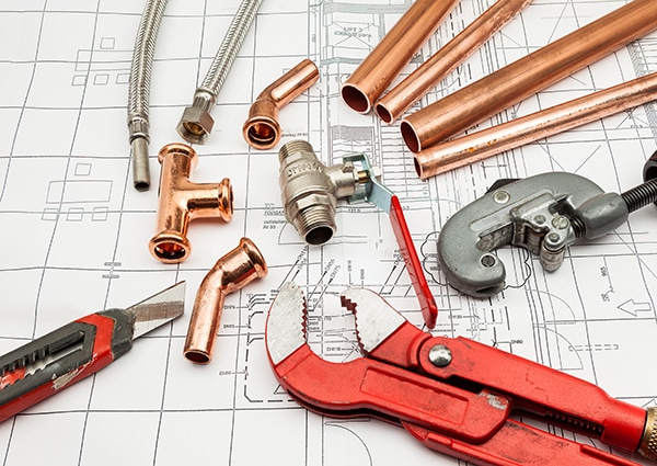 Plan plumber Plumbing tools and copper pipes on construction blueprint, featuring wrench, cutter, fittings, and flexible hoses. | Sky Rye Design Plumbing tools and copper pipes on construction blueprint, featuring wrench, cutter, fittings, and flexible hoses.