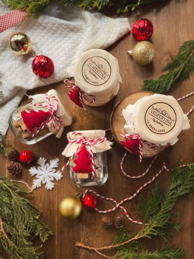 Festive holiday jars with red and gold ornaments, pine branches, and a cozy winter theme on a wooden table.