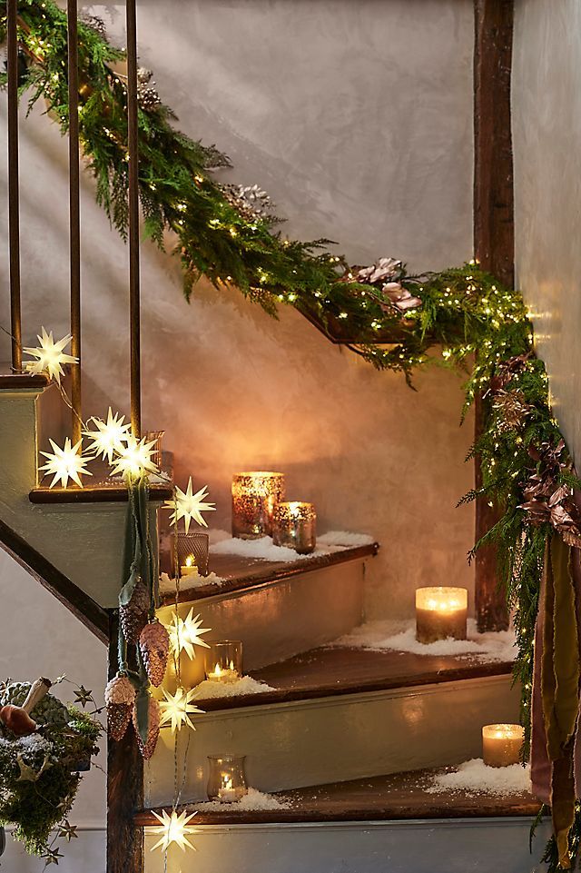 Cozy holiday staircase with candles, pine garlands, and star lights creating a warm festive ambiance.