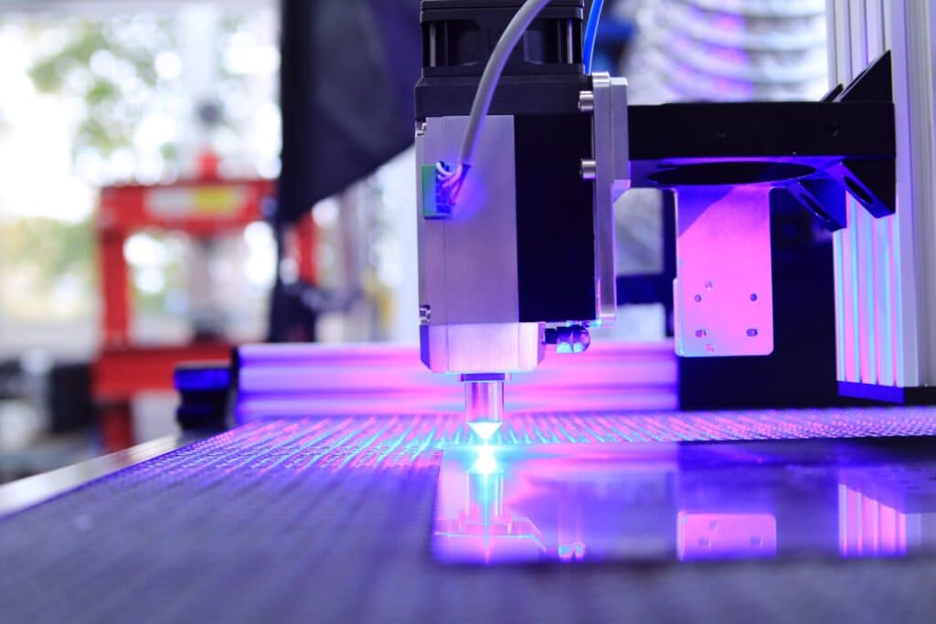 REV-types-of-metal-3d-printing High-tech laser machine operating with precision and emitting blue light on a reflective surface. | Sky Rye Design High-tech laser machine operating with precision and emitting blue light on a reflective surface.