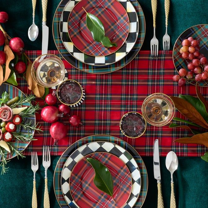 Festive table setting with plaid patterns, elegant dishware, fruit, and greenery, perfect for a holiday celebration.